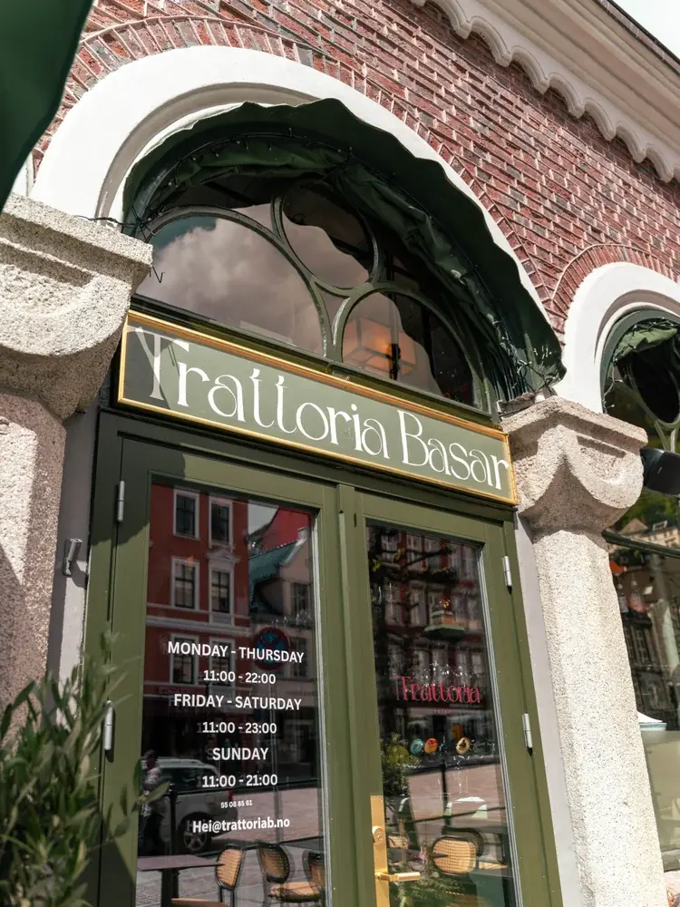 Inngangen til Trattoria Basar i Kjøttbasaren med åpningstider på døren